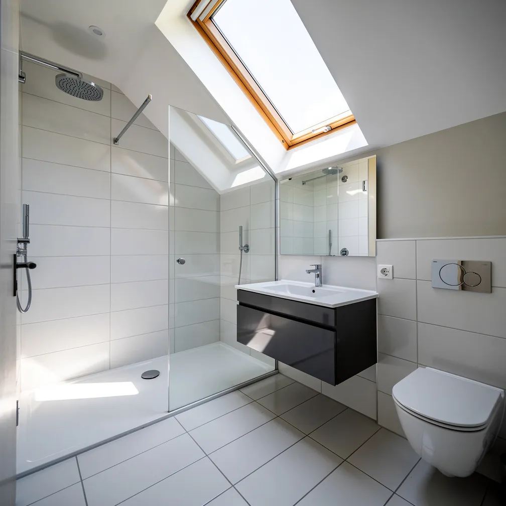 Petite salle de bain sous comble avec douche sous la partie haute et velux