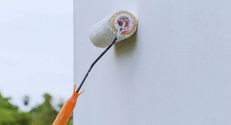 Rouleau de peinture blanche en train de peindre un mur exterieur