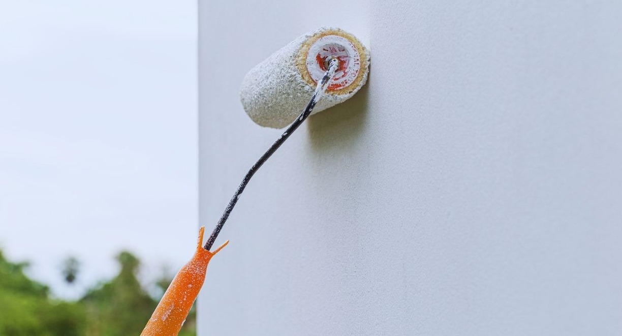 Rouleau de peinture blanche en train de peindre un mur exterieur