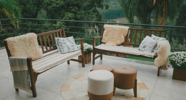 Terrasse exterieure avec bancs en bois coussins et vue sur la verdure