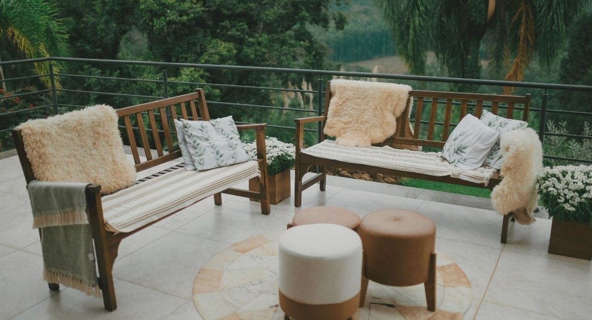 Terrasse exterieure avec bancs en bois coussins et vue sur la verdure